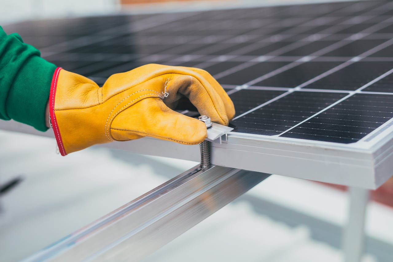 about-bg Close-up of a worker's hand with protective gloves adjusting a bolt on a solar panel.