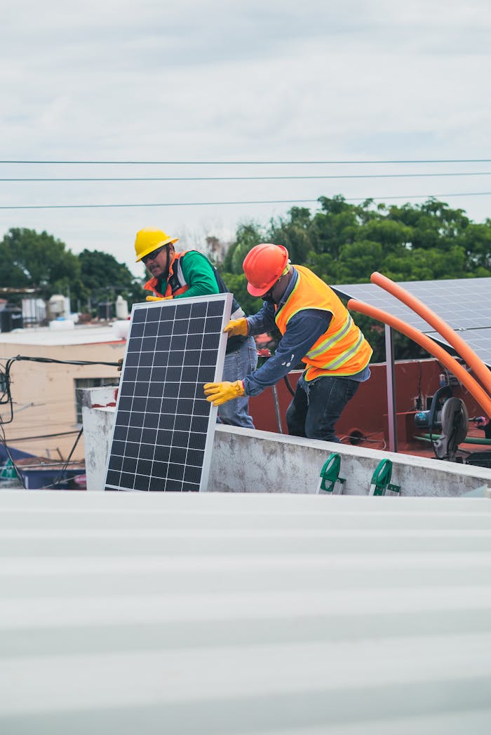 services-04 Two workers in safety gear installing solar panels on a rooftop for sustainable energy.