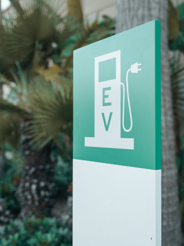 get-in-touch Close-up of a green and white electric vehicle charging station sign with nature background.